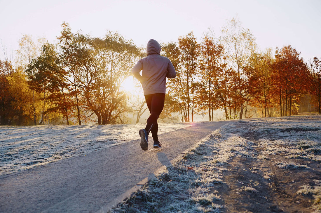 Athlete runs on a trail with snow on the ground.