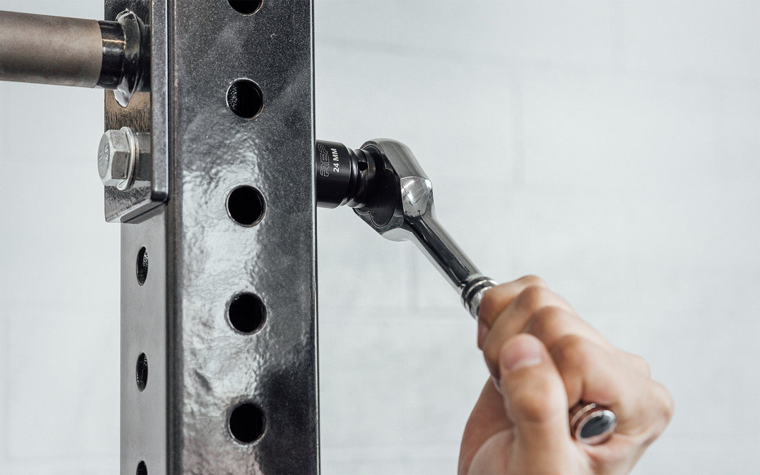 Man uses a socket to put together a power rack.