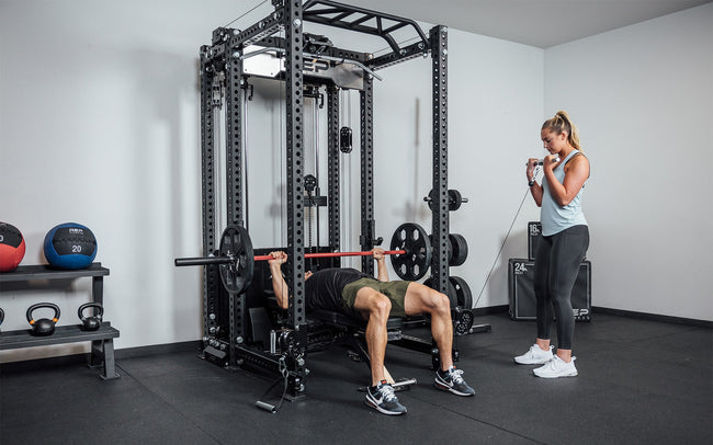 One athlete doing bench press in the rack while the other uses the front trolley of the Ares 2.0 for other exercises.