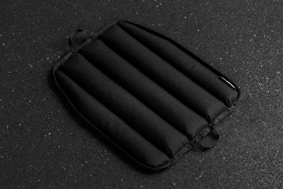 Black soft weight vest plate with ribbed texture on a dark textured background